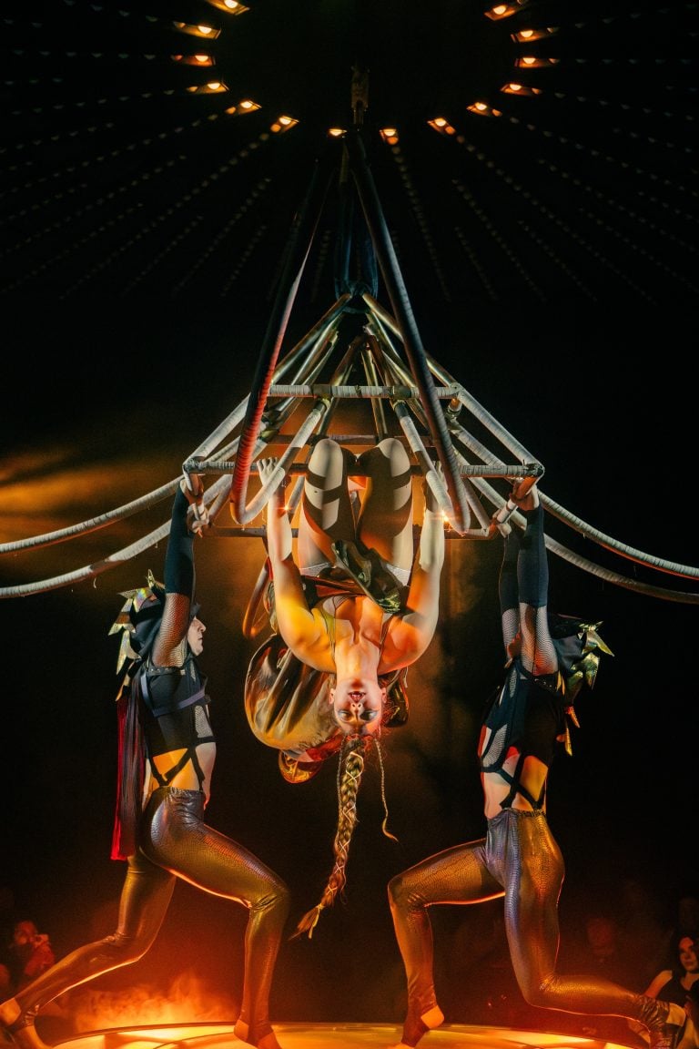 Performers in Moonrise hang upside down from a large, spiky wood structure