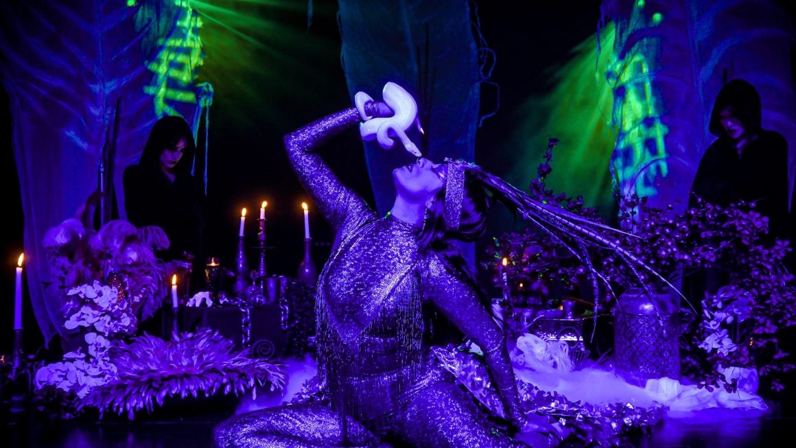 A performer in Moonrise holds a snake close to her face
