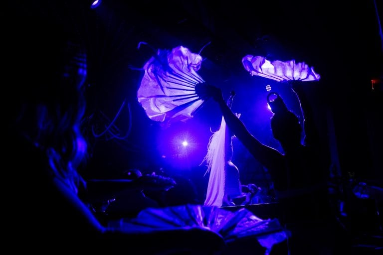 A silhouetted figure with two silk fans