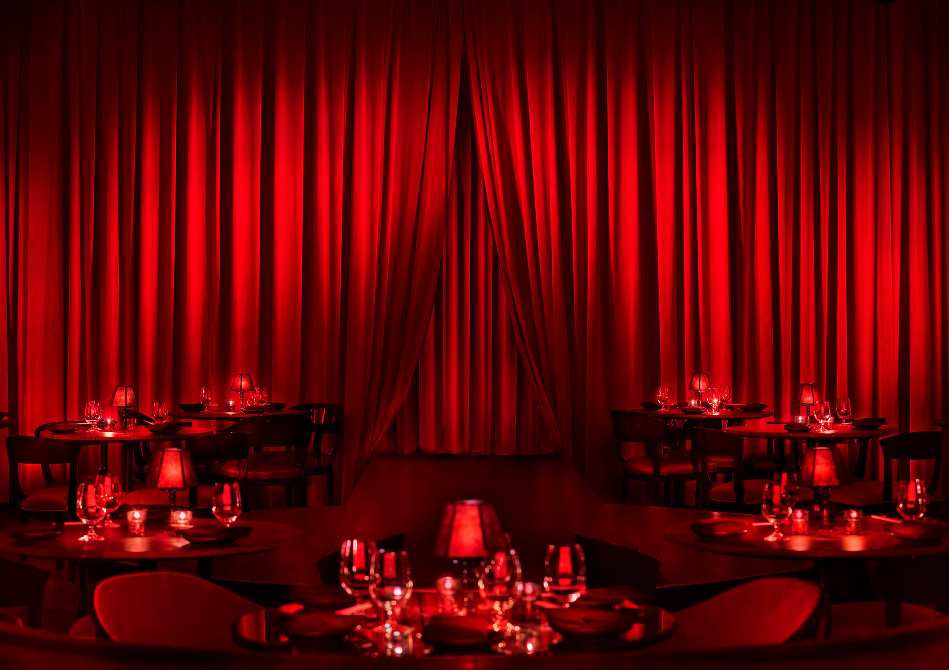 A few cabaret tables in front of a red curtain