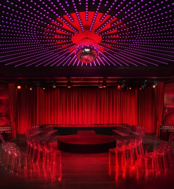 a stage surrounded by clear chairs at the Paradise Club in NYC