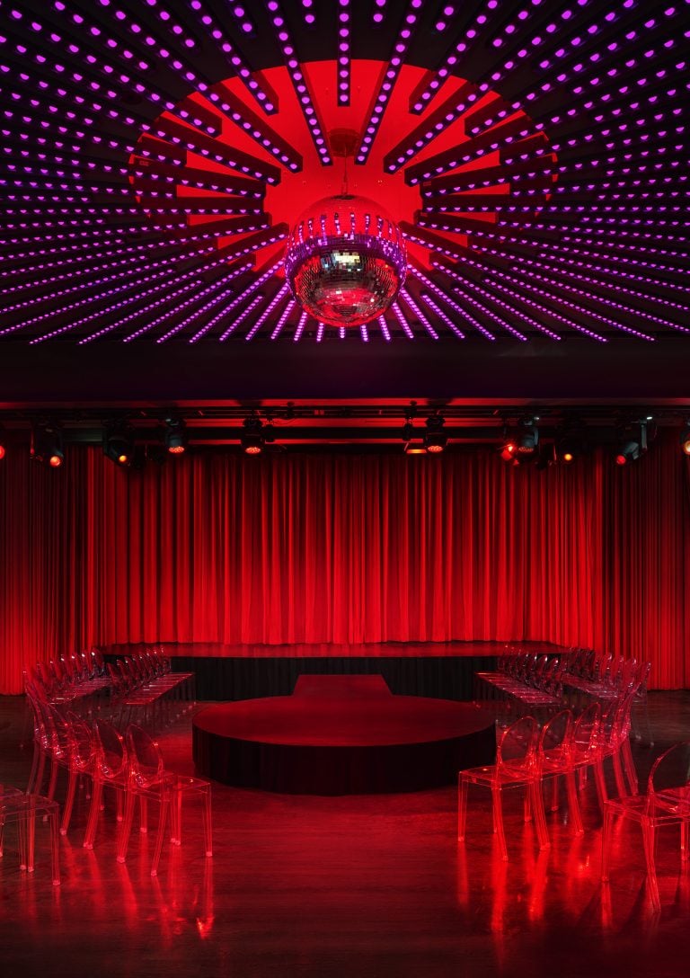 a stage surrounded by clear chairs at the Paradise Club in NYC